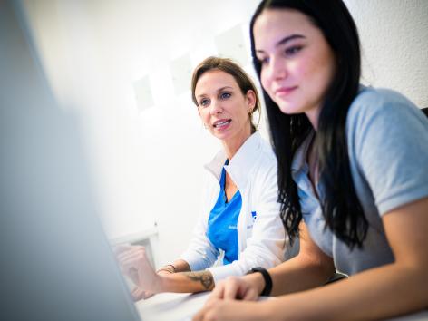 Zwei medizinische Fachkräfte sitzen gemeinsam vor einem Computerbildschirm